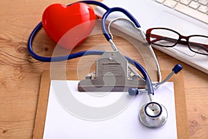 Medical stethoscope lying on a computer keyboard, documents