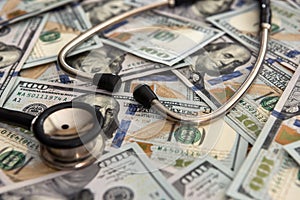 Medical stethoscope lying on a lot dollar banknotes