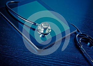 Medical stethoscope on modern digital tablet in laboratory on wood table