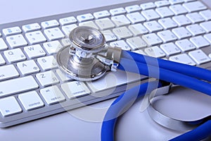 A medical stethoscope near a laptop on a wooden table