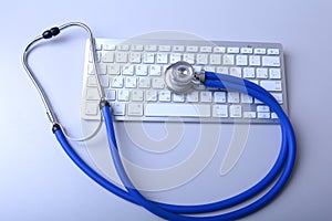 A medical stethoscope near a laptop on a wooden table