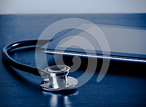 Medical stethoscope near modern digital tablet pc in laboratory on wood table