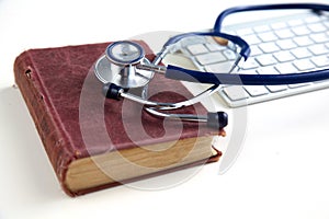 Medical stethoscope with old books and laptop on a