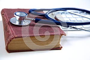 Medical stethoscope with old books and laptop on a
