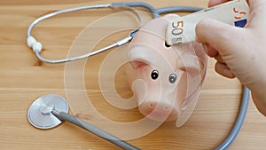 Medical stethoscope and piggy bank on the table. Investment in health insurance