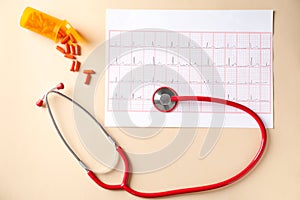 Medical stethoscope, pills and cardiogram on light background