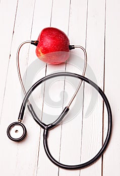Medical stethoscope and red apple on a white table