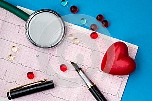 Medical stethoscope and red heart on cardiogram chart pen