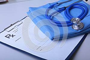 A medical stethoscope and RX prescription are lying on a medical uniform