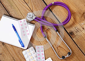 Medical stethoscope and tablets isolated on wooden background