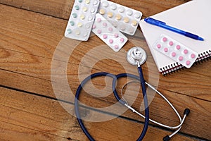 Medical stethoscope and tablets isolated on wooden background