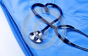 Medical stethoscope twisted in heart shape lying on patient medical history list and blue doctor uniform closeup