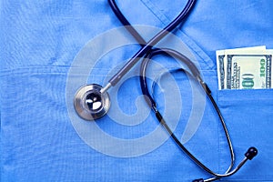 Medical stethoscope twisted in heart shape lying on patient medical history list and blue doctor uniform closeup