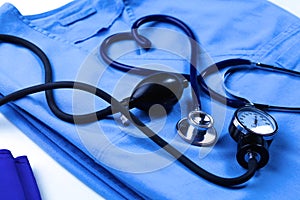 Medical stethoscope twisted in heart shape lying on patient medical history list and blue doctor uniform closeup