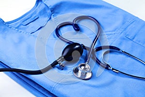 Medical stethoscope twisted in heart shape lying on patient medical history list and blue doctor uniform closeup