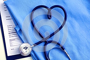 Medical stethoscope twisted in heart shape lying on patient medical history list and blue doctor uniform closeup