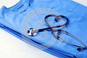 Medical stethoscope twisted in heart shape lying on patient medical history list and blue doctor uniform closeup