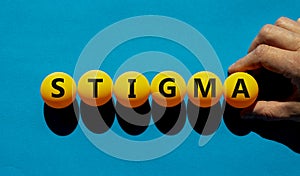 Medical and stigma symbol. The concept word `stigma` on orange table tennis balls on a beautiful blue background. Doctor hand.