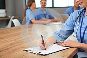 Medical student with clipboard and her groupmates studying in university library