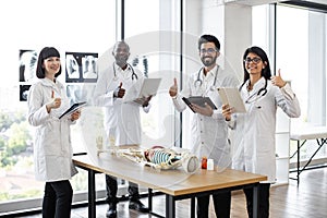 Medical students on anatomy lesson in classroom showing, thumbs up