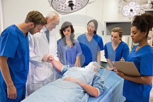 Medical students and professor checking pulse of student