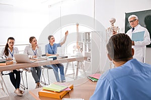 Medical students and professor studying human skeleton anatomy