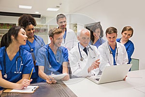 Medical students and professor using laptop