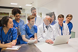 Medical students and professor using laptop