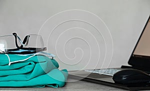 a medical suit and glasses lie near a laptop on the table, a doctor's office, medicine, medical