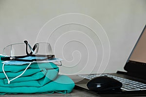 a medical suit and glasses lie near a laptop on the table, a doctor's office, medicine, medical