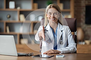 Medical Support. Smiling Female Doctor Extending Hand For Handshake At Camera