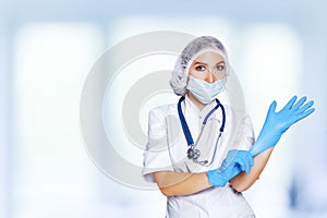 Medical surgeon doctor woman over blue clinic background. Doctor putting on sterile gloves. Place for medical advertise