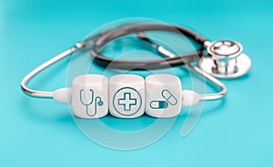 Medical symbols on cube shape blocks and Stethoscope on blue background