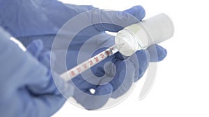 Medical  syringe and blue cloves taking medicine out of a medical bottle
