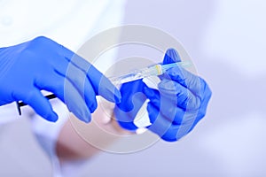 Medical syringe on hand of the doctor during pandemic covid-19. Hand of a doctor holding medical syringe with coronavirus vaccine.