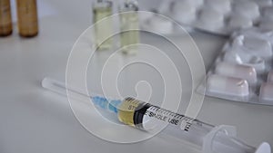 Medical syringe with injection solution, medicine pills and capsules on white background