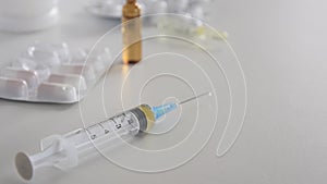 Medical syringe with injection solution, medicine pills and capsules on white background