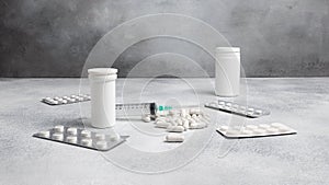 medical syringe, medicine pills, capsules, vials on grey concrete background