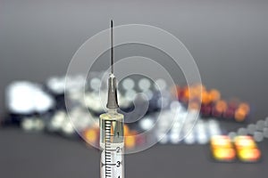 Medical syringe with a needle and colorful pills capsule on background