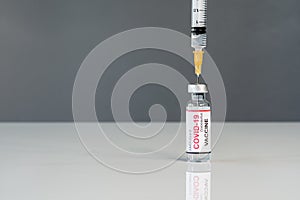 Medical syringe needle drawing Coronavirus Covid-19 vaccine shot from glass of bottle