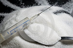 Medical syringe, pile of sugar grain in table spon, concept of d