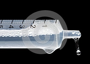 Medical syringe showing liquid bubbling and dripping has its expelled under pressure from syringe