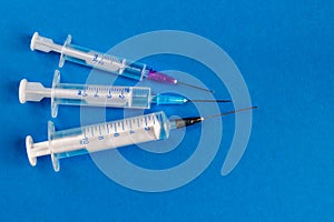 Medical syringes of different capacities lie on a blue surface photo