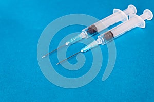Medical syringes of different capacities lie on a blue surface