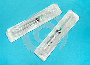 Medical syringes in packages close-up view from above on a blue background. Syringes for inoculations. Healthcare and medicine.