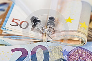 Medical syringes on wad of several euro banknotes bills