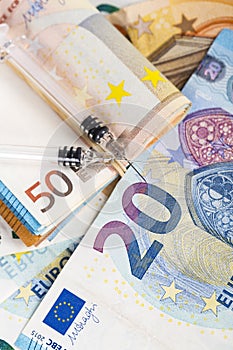 Medical syringes on wad of several euro banknotes bills