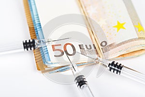 Medical syringes on wad of several euro banknotes bills