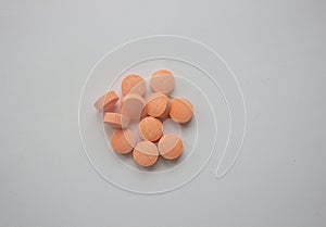 Medical tablets under a magnifying glass on a white background.