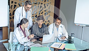 Medical team discussing over digital tablet at table in the hospital